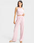 Woman wearing a pink one-shoulder top and wide-leg pants on a white background