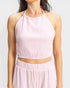 Woman wearing a light pink ribbed halter top and skirt set on a white background