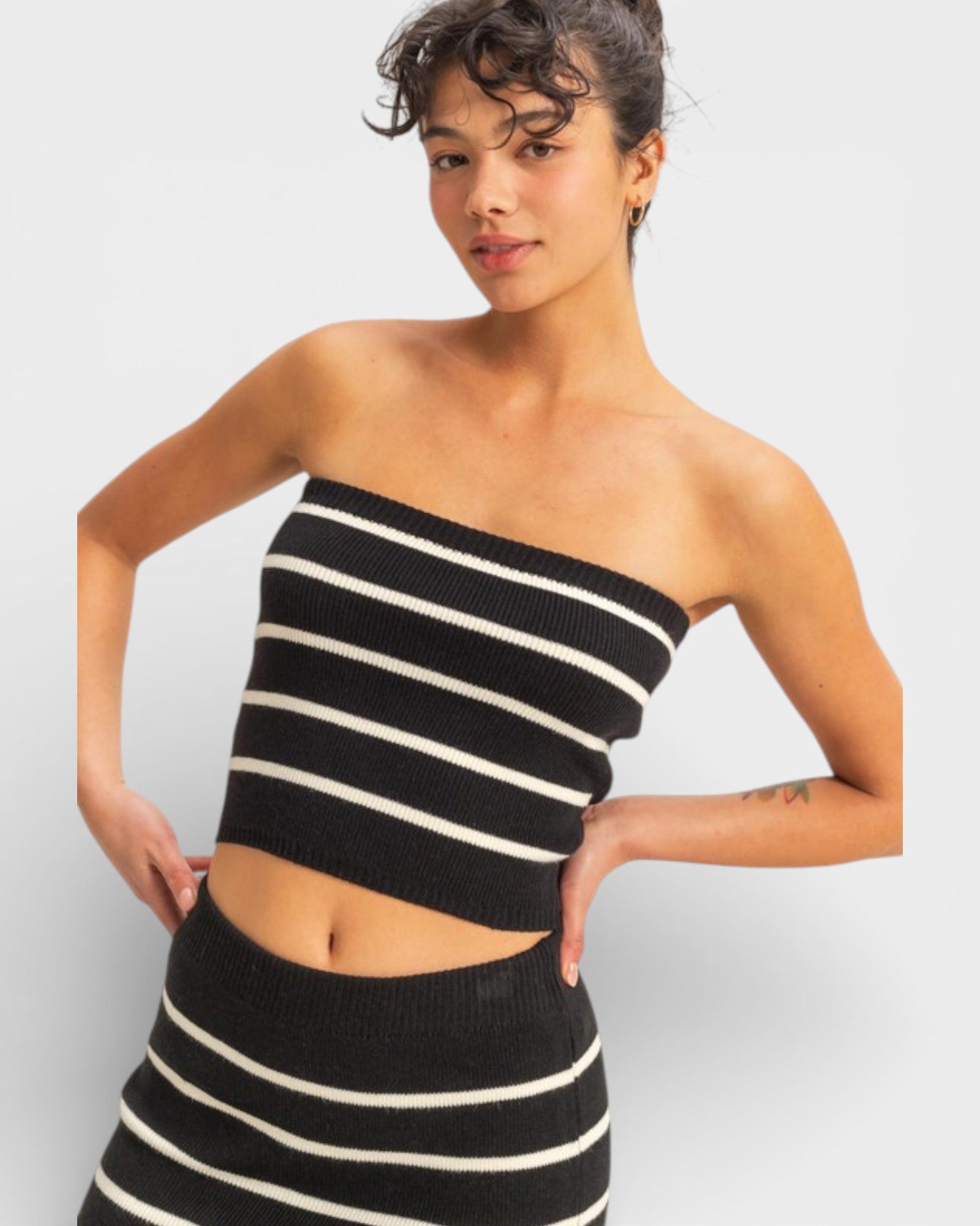 Woman wearing a black and white striped dress against a plain background