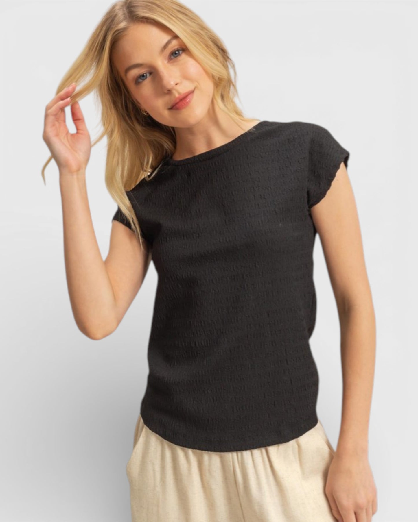 Woman wearing a black short-sleeve top against a light gray background