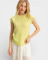 Woman wearing a light green sleeveless top and white skirt on a plain background