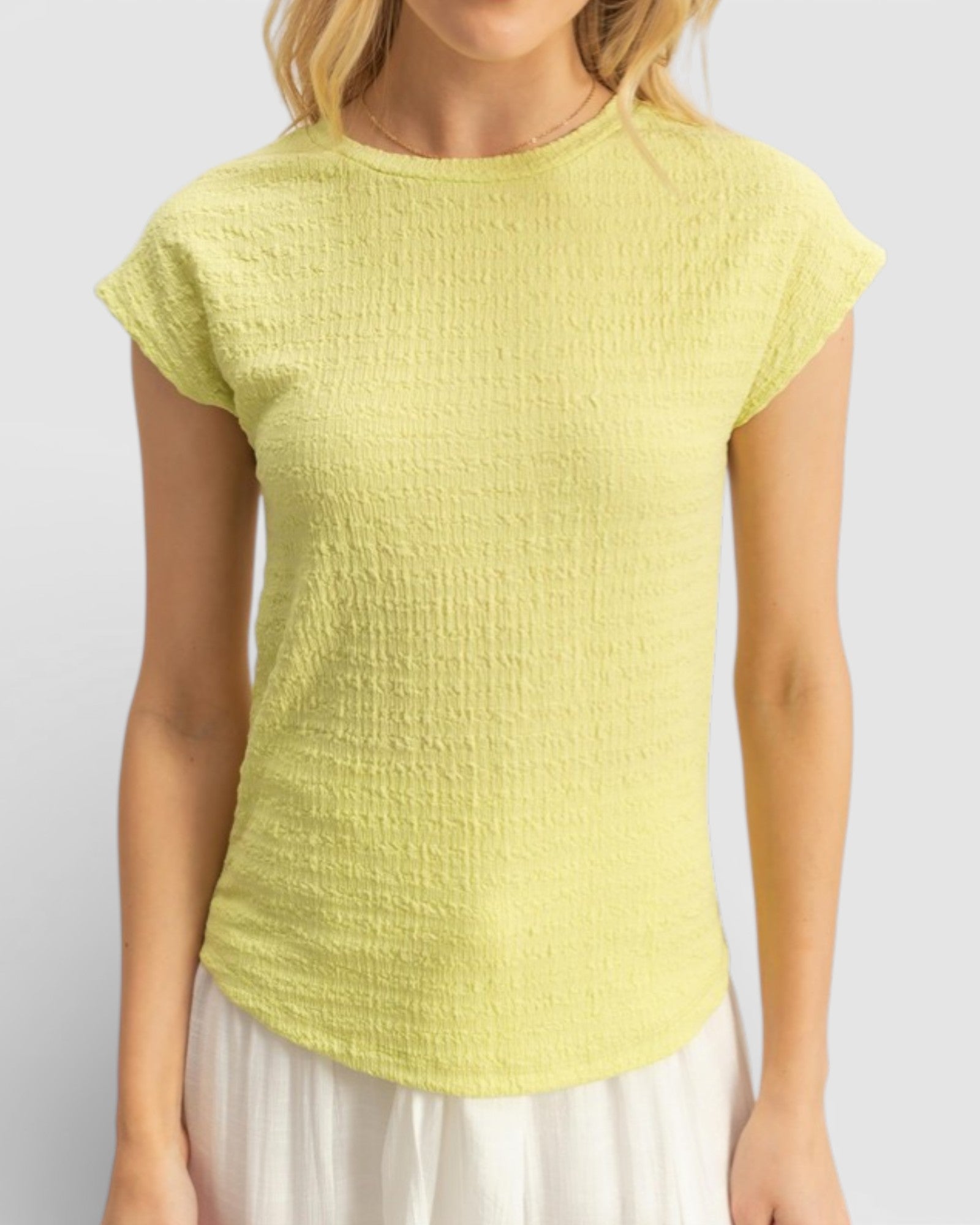 Woman wearing a yellow textured top against a plain background