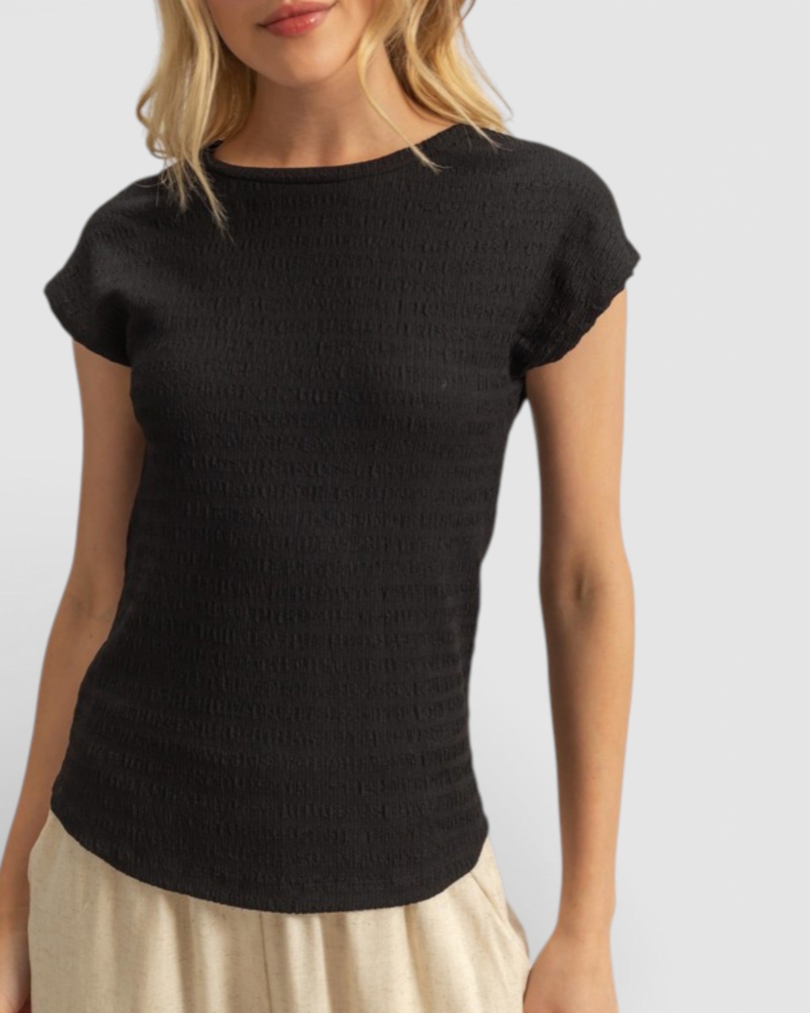 Person wearing a black short-sleeve top against a plain background