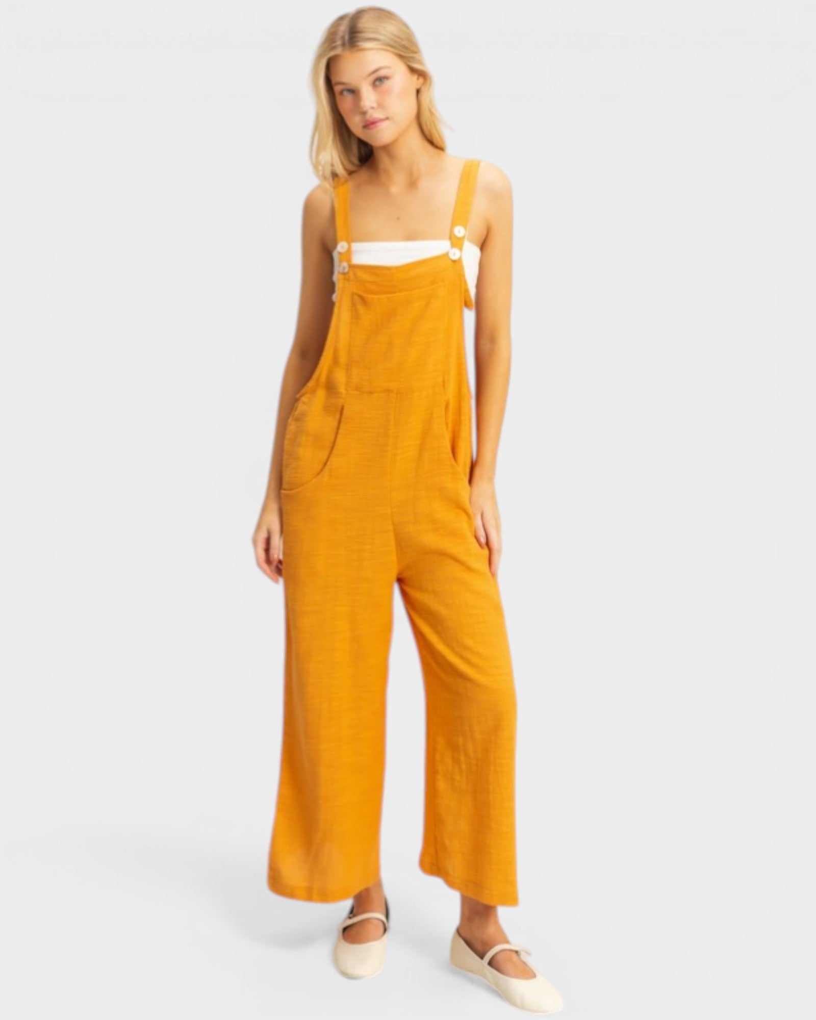 Woman wearing mustard yellow overalls on a white background