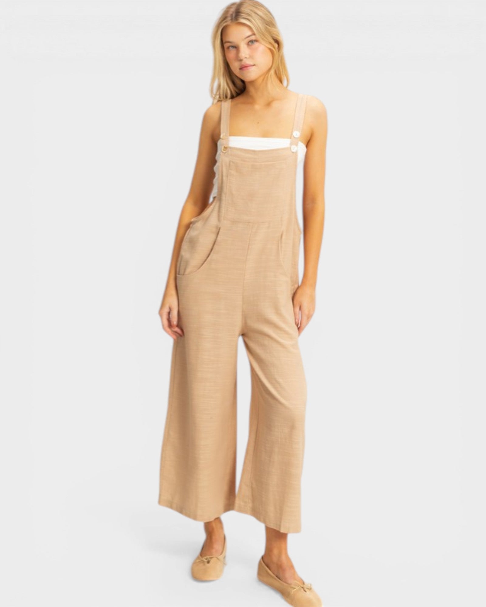 Woman wearing a beige jumpsuit on a white background