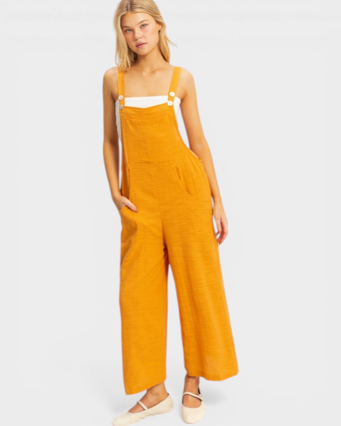 Woman wearing mustard yellow overalls on a white background