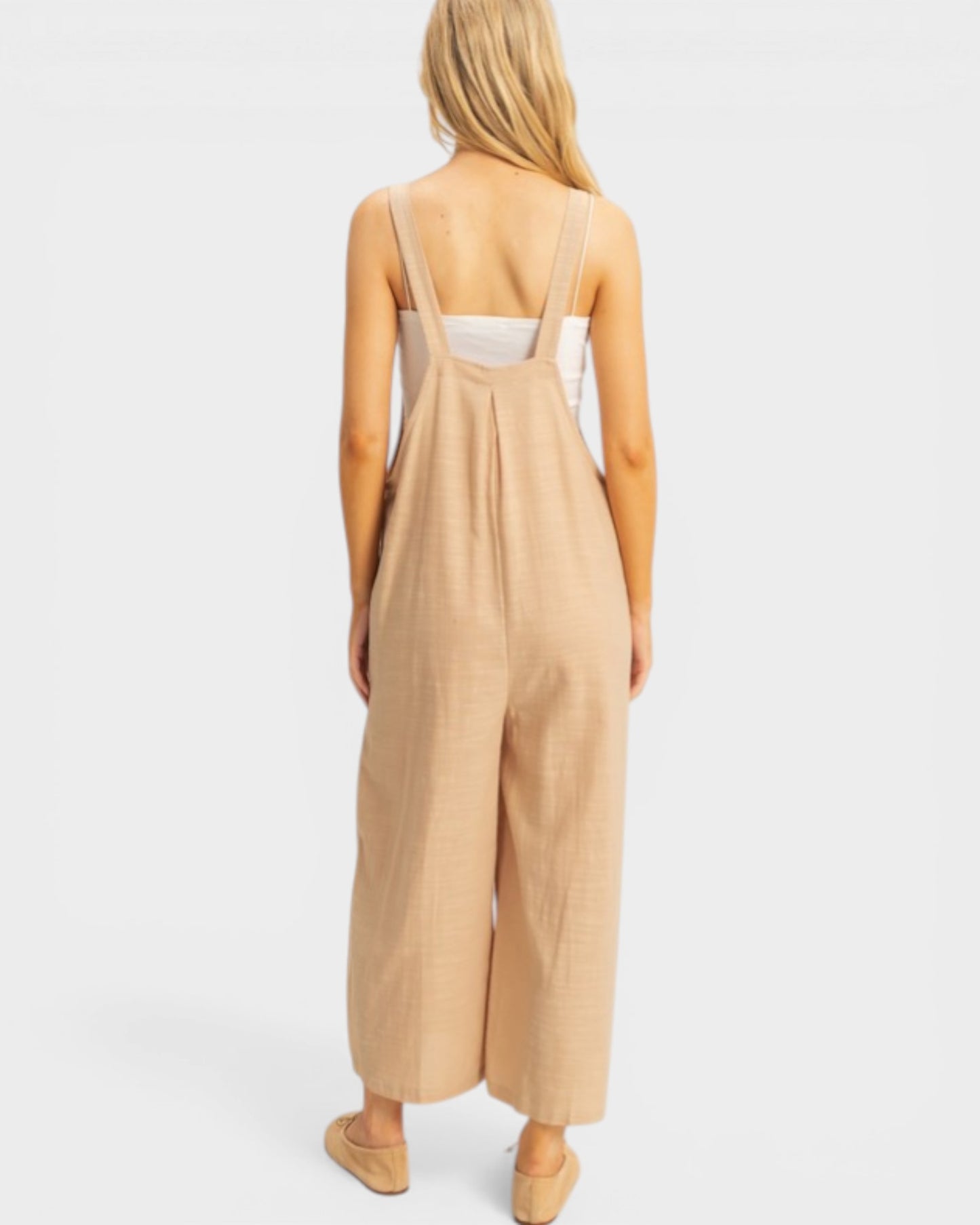 Woman wearing a beige jumpsuit on a white background