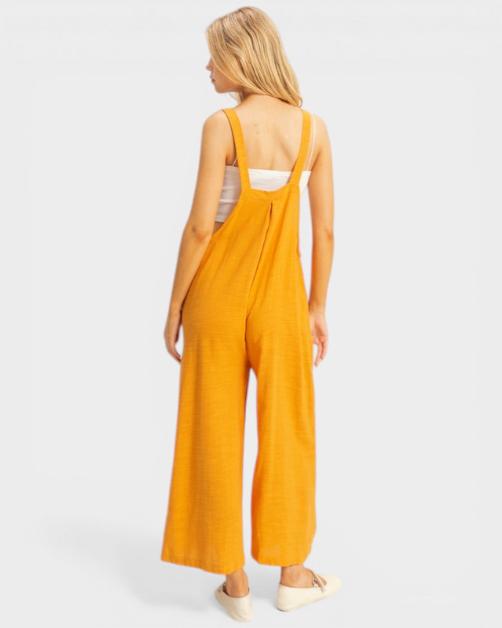 Woman wearing a yellow jumpsuit on a white background