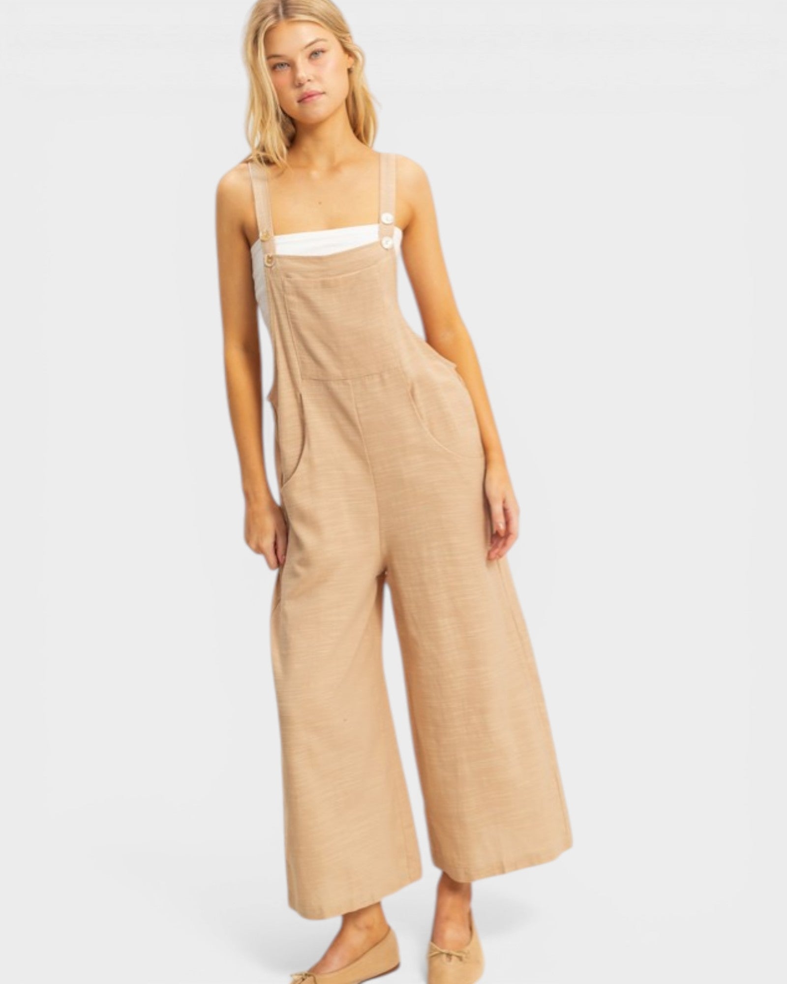 Woman wearing beige overalls on a white background