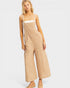 Woman wearing beige overalls on a white background
