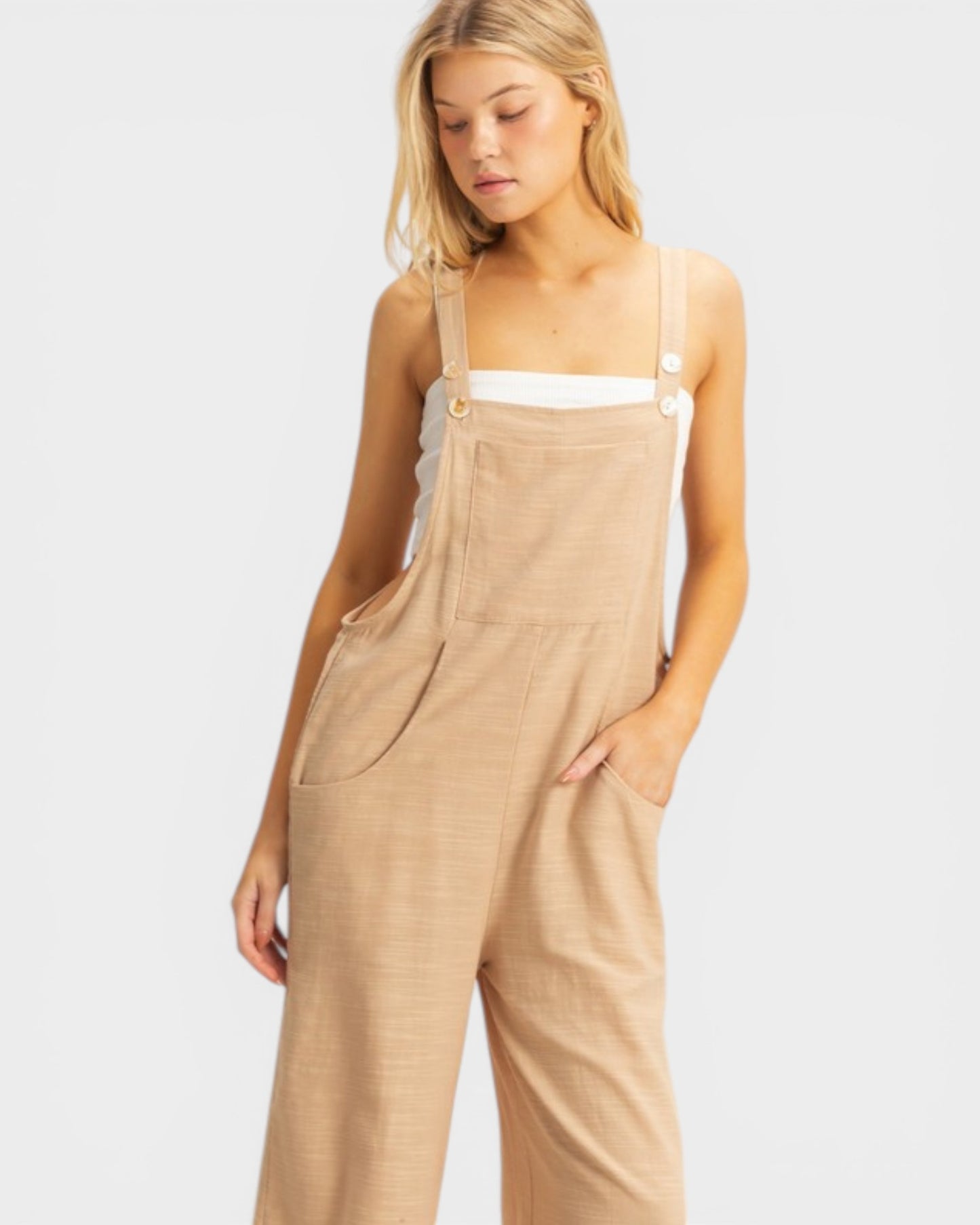 Woman wearing beige overalls on a white background