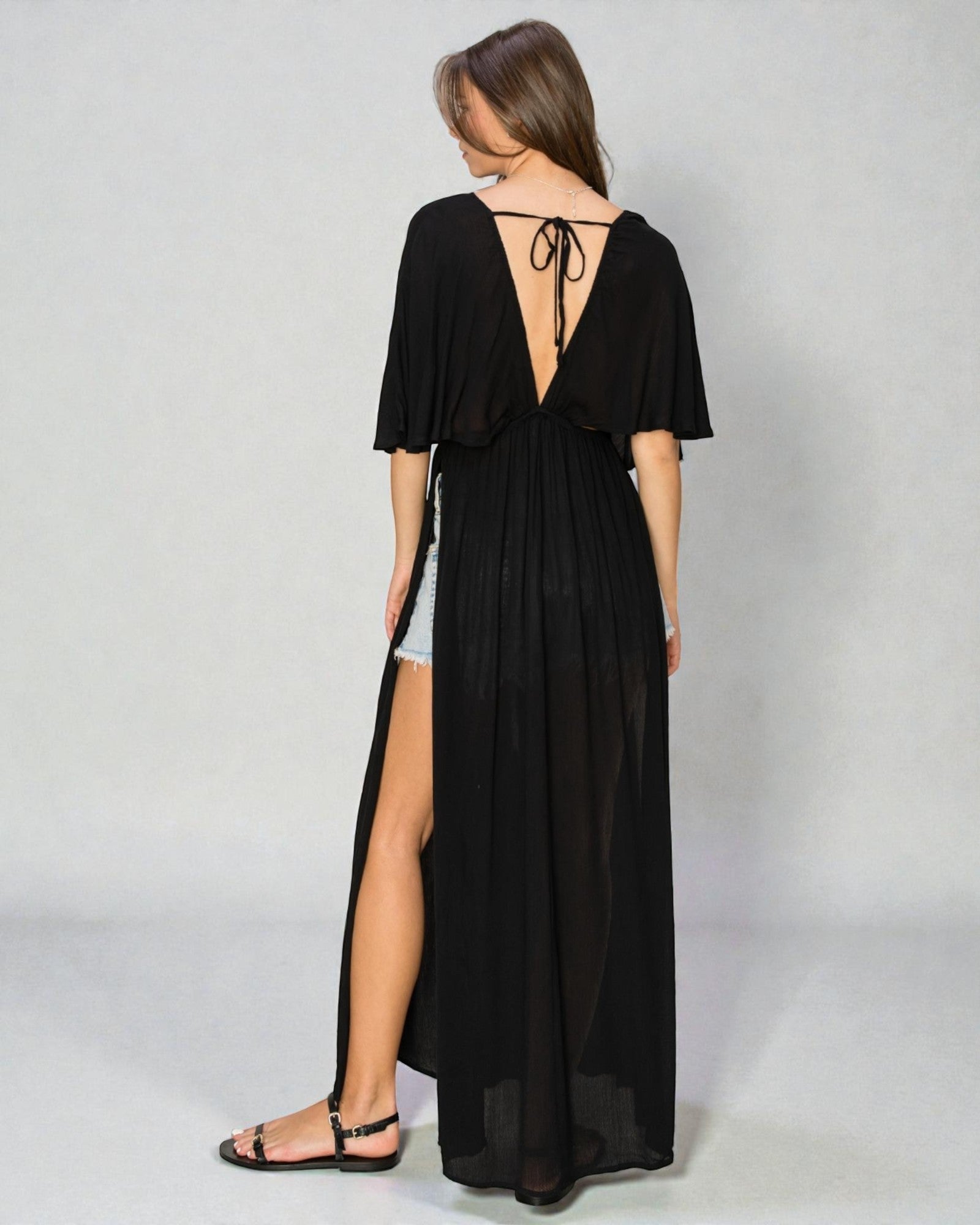 Woman wearing a black dress with a slit on a gray background