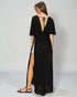 Woman wearing a black dress with a slit on a gray background