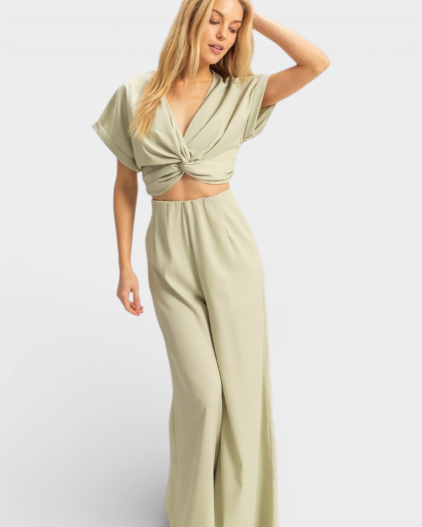 Woman wearing a light green outfit with a top and pants on a white background