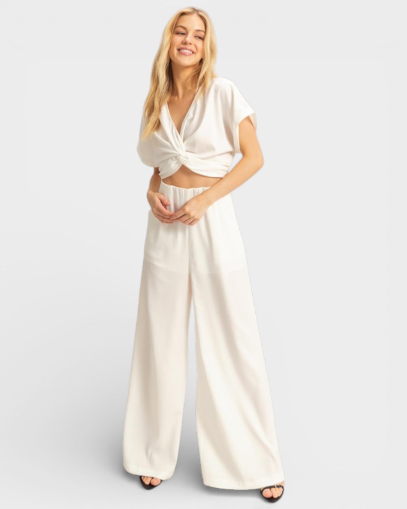 Woman wearing a white outfit with wide-leg pants on a light gray background