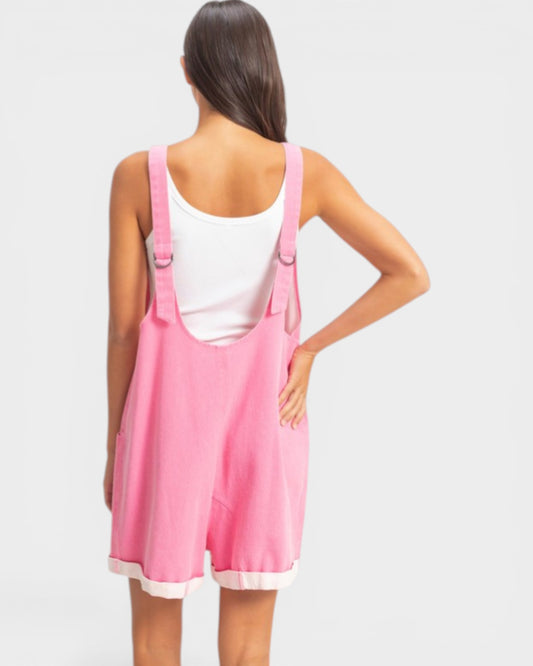 Person wearing a pink dress with straps on a plain background