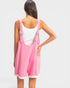 Person wearing a pink dress with straps on a plain background