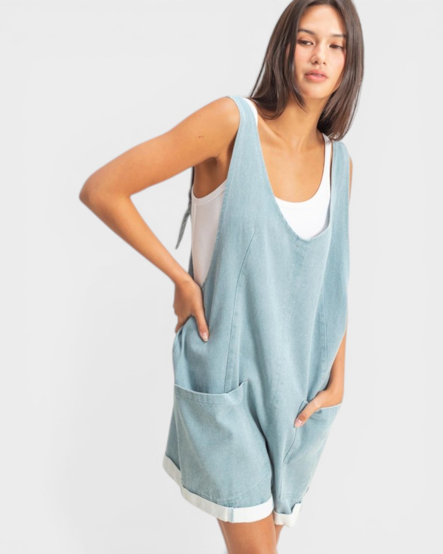 Woman wearing a light blue sleeveless top and shorts on a white background