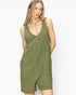 A woman modeling an olive green sleeveless romper with a deep V-neck and front patch pockets, set against a plain white studio background.