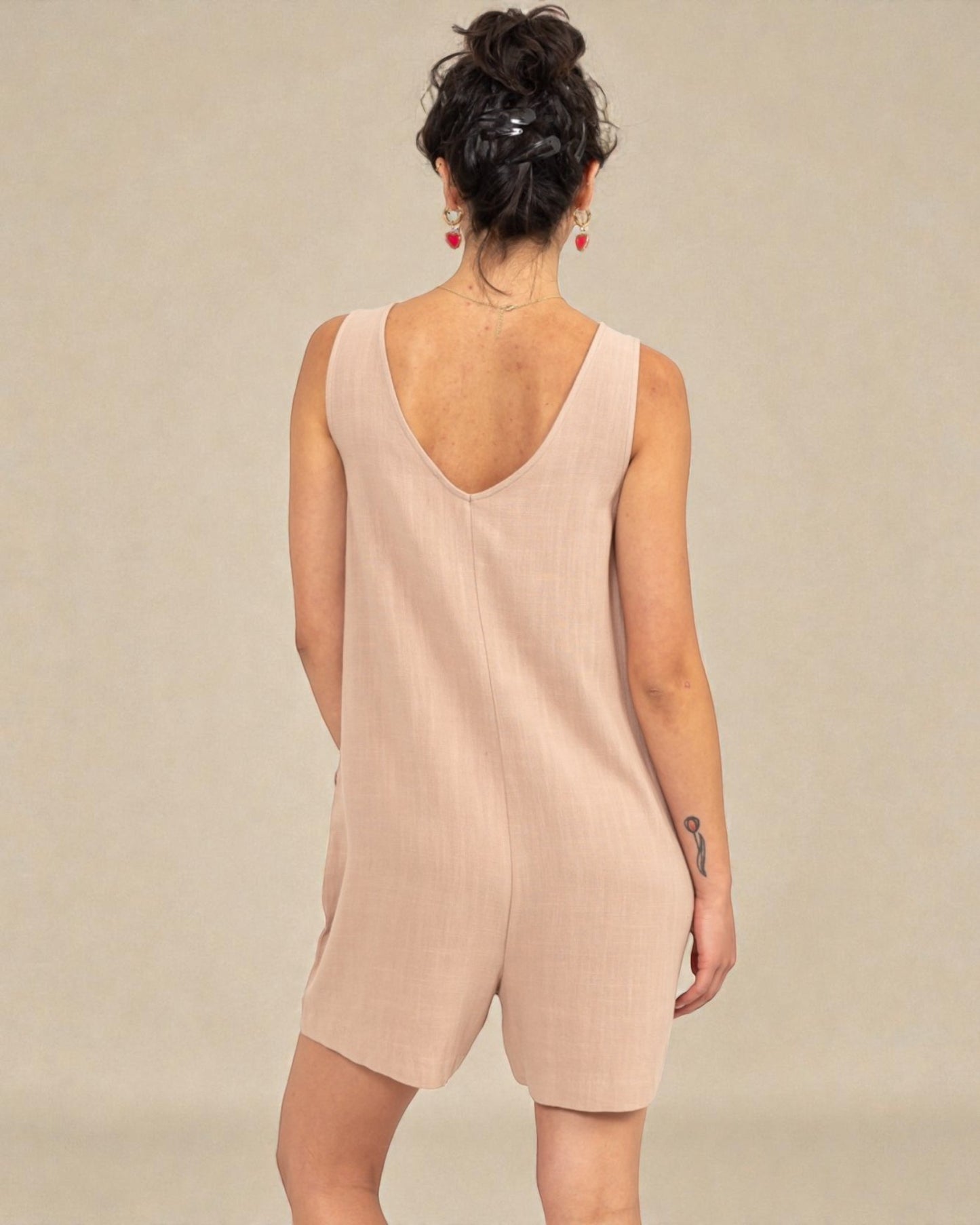 Woman wearing a beige sleeveless dress against a plain background