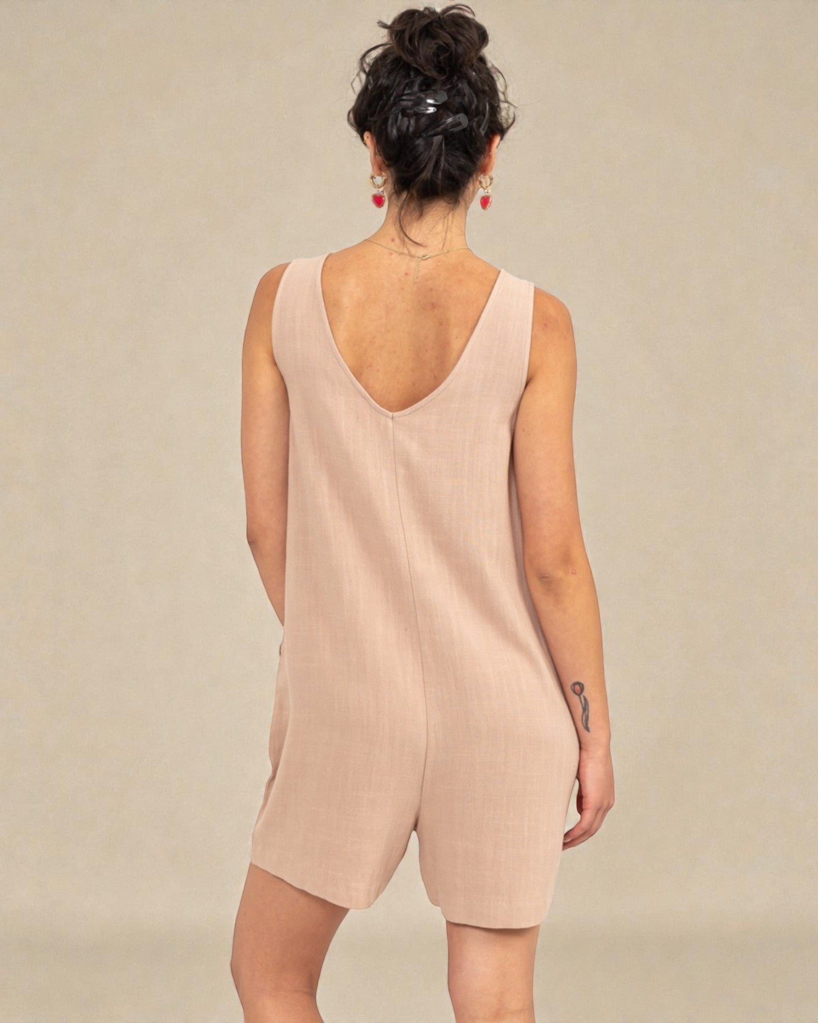 Woman wearing a beige sleeveless dress against a plain background