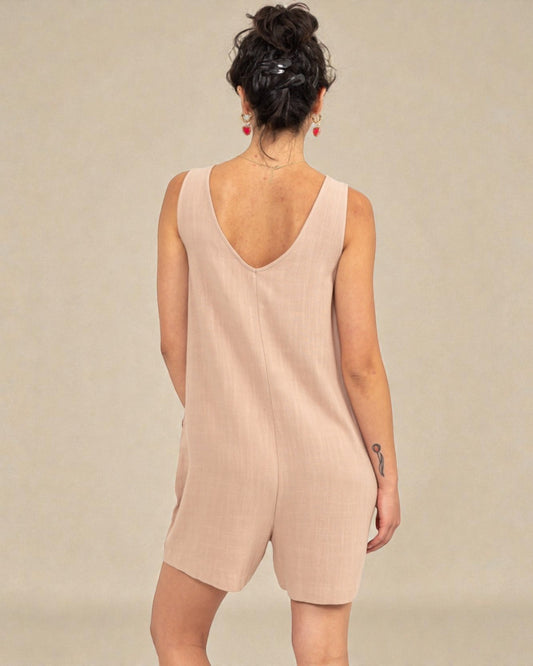 Woman wearing a beige sleeveless dress against a plain background