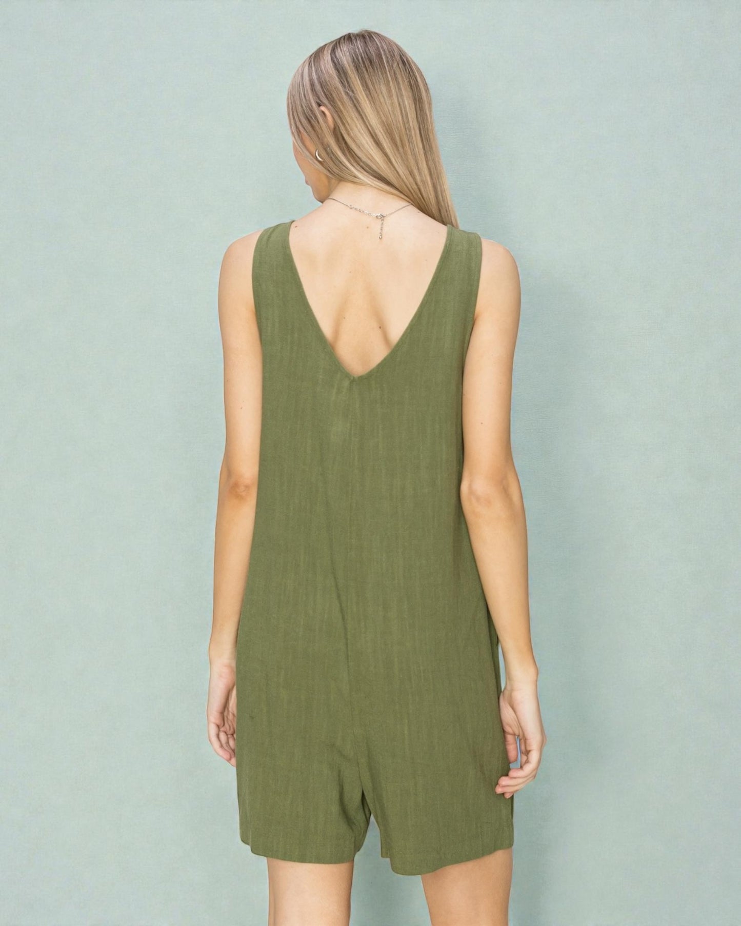 Person wearing a green romper against a plain background