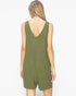 A woman viewed from the back wearing an olive green sleeveless romper with a deep V-neck and short legs, set against a plain white background.