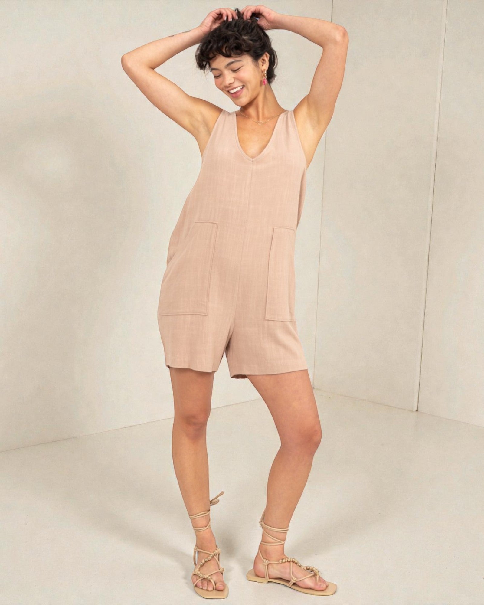 Woman wearing a beige sleeveless dress against a plain background