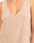 Close-up of a sleeveless V-neck top in a light blush beige fabric, shown on a model.