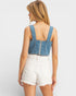 Woman wearing a denim crop top and white shorts on a plain background