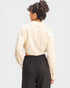 Person wearing a beige shirt and black pants on a light gray background