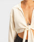 Beige open-back top worn by a person on a white background