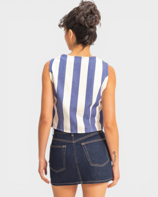 Person wearing a blue and white striped sleeveless top with a denim skirt on a plain background