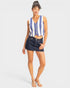 Woman wearing a blue and white striped sleeveless top and denim skirt on a light gray background