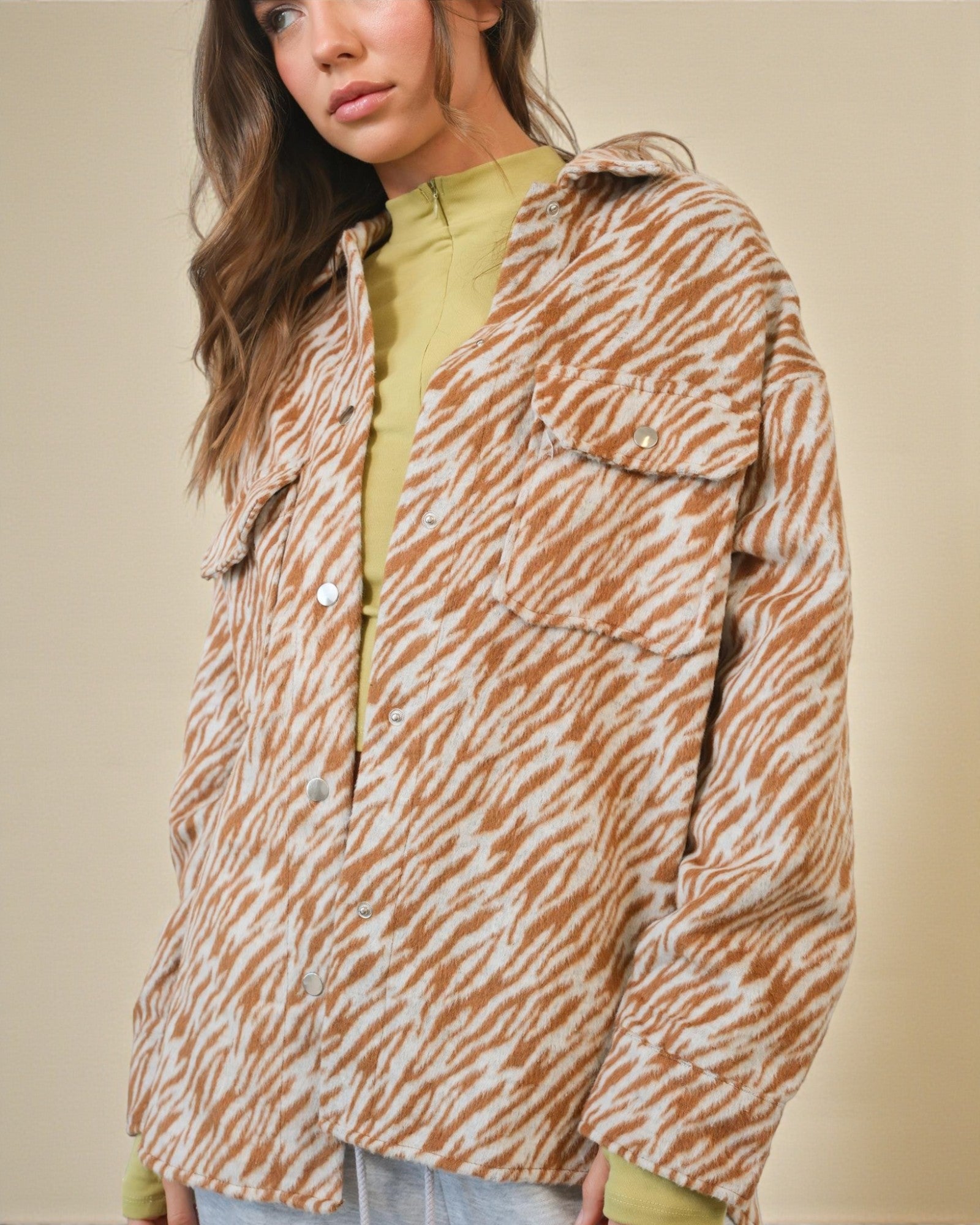 Person wearing a zebra print jacket over a green top on a beige background