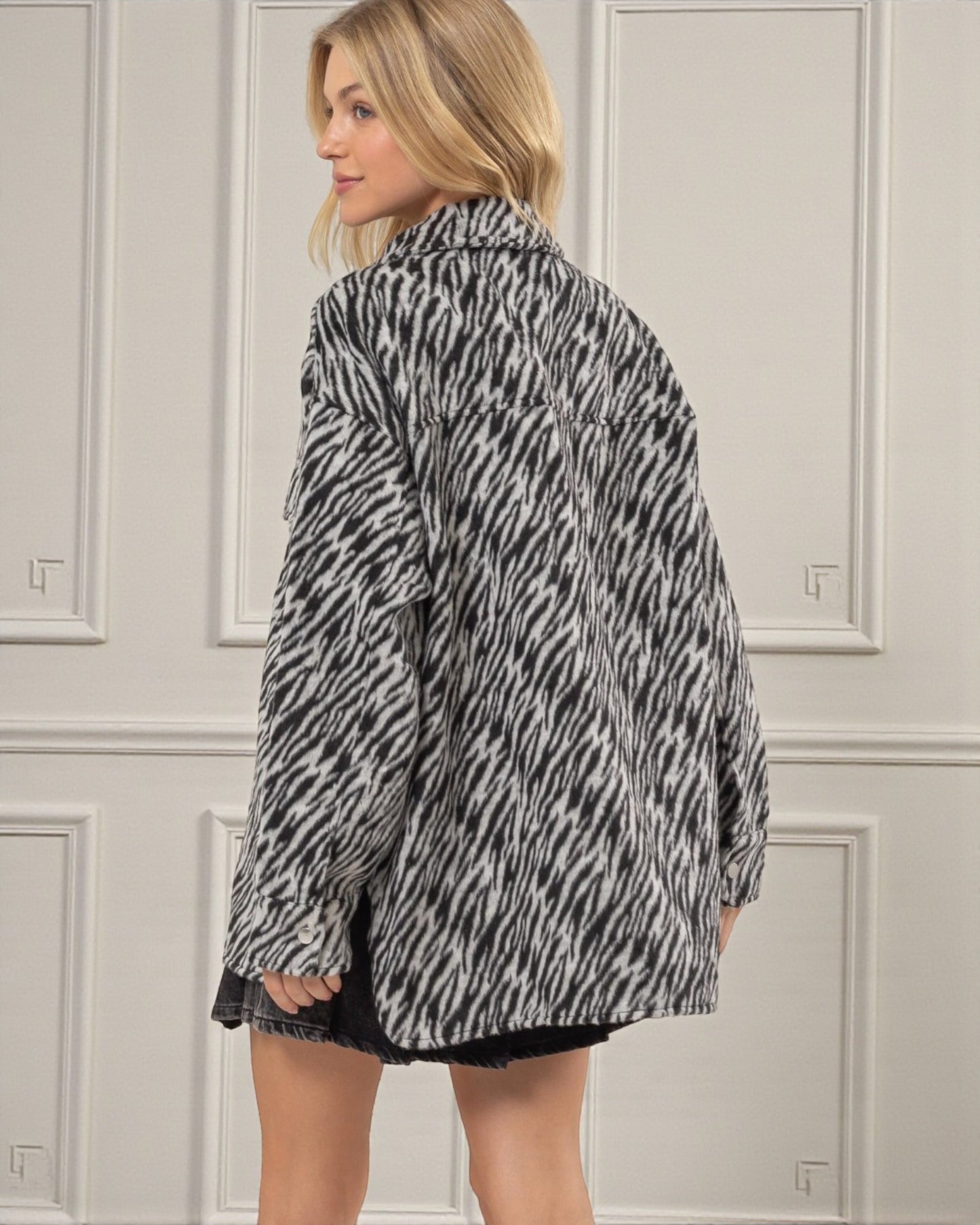 Woman wearing a zebra print jacket against a neutral background