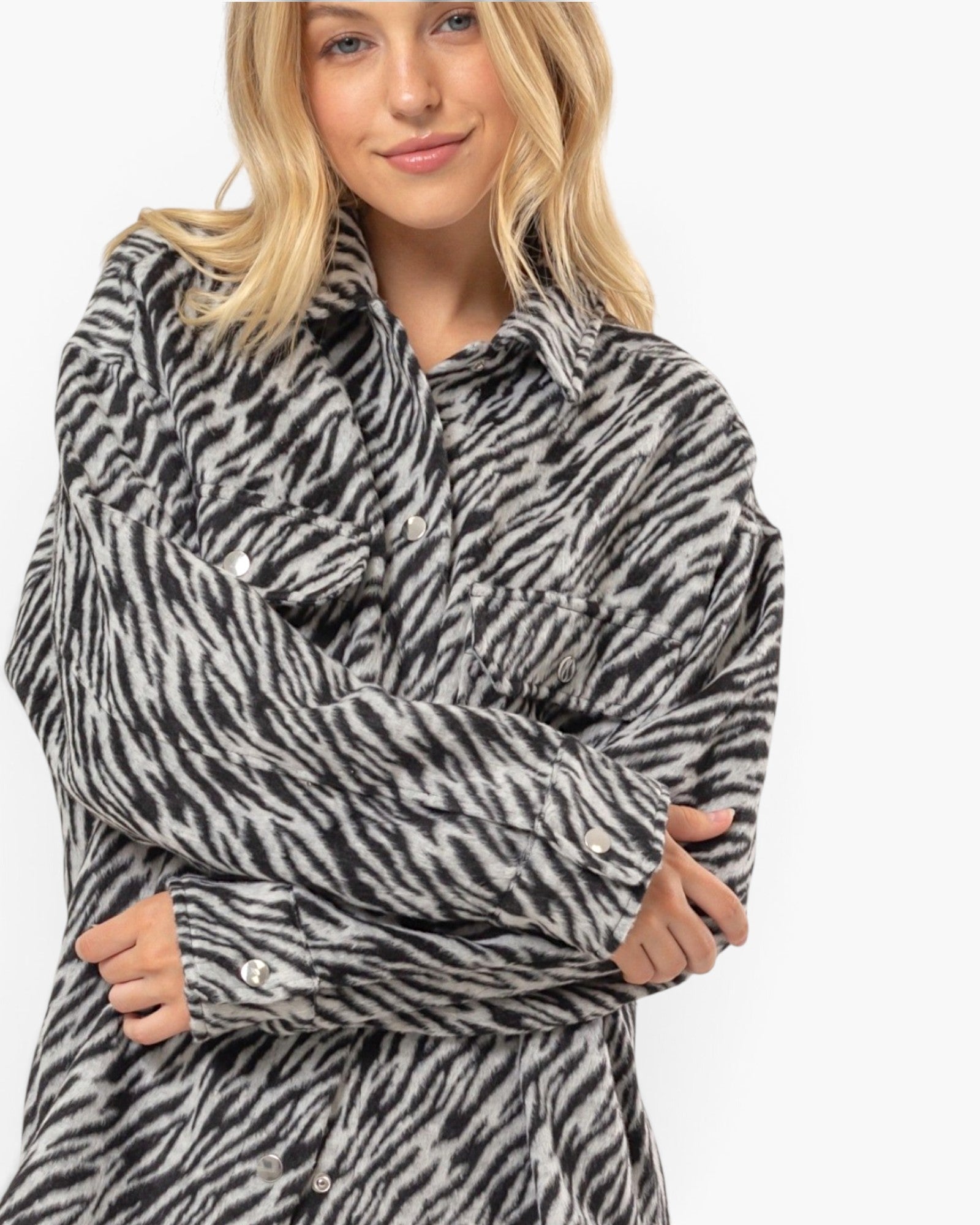 A woman wearing a black and white zebra-print button-up shirt jacket, shown from the chest up against a plain white studio background.