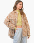 A woman modeling an oversized brown and beige zebra-print jacket over a yellow-green crop top and light gray sweatpants, photographed against a clean white studio background.