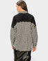 Person wearing a black and white checkered shirt on a light gray background
