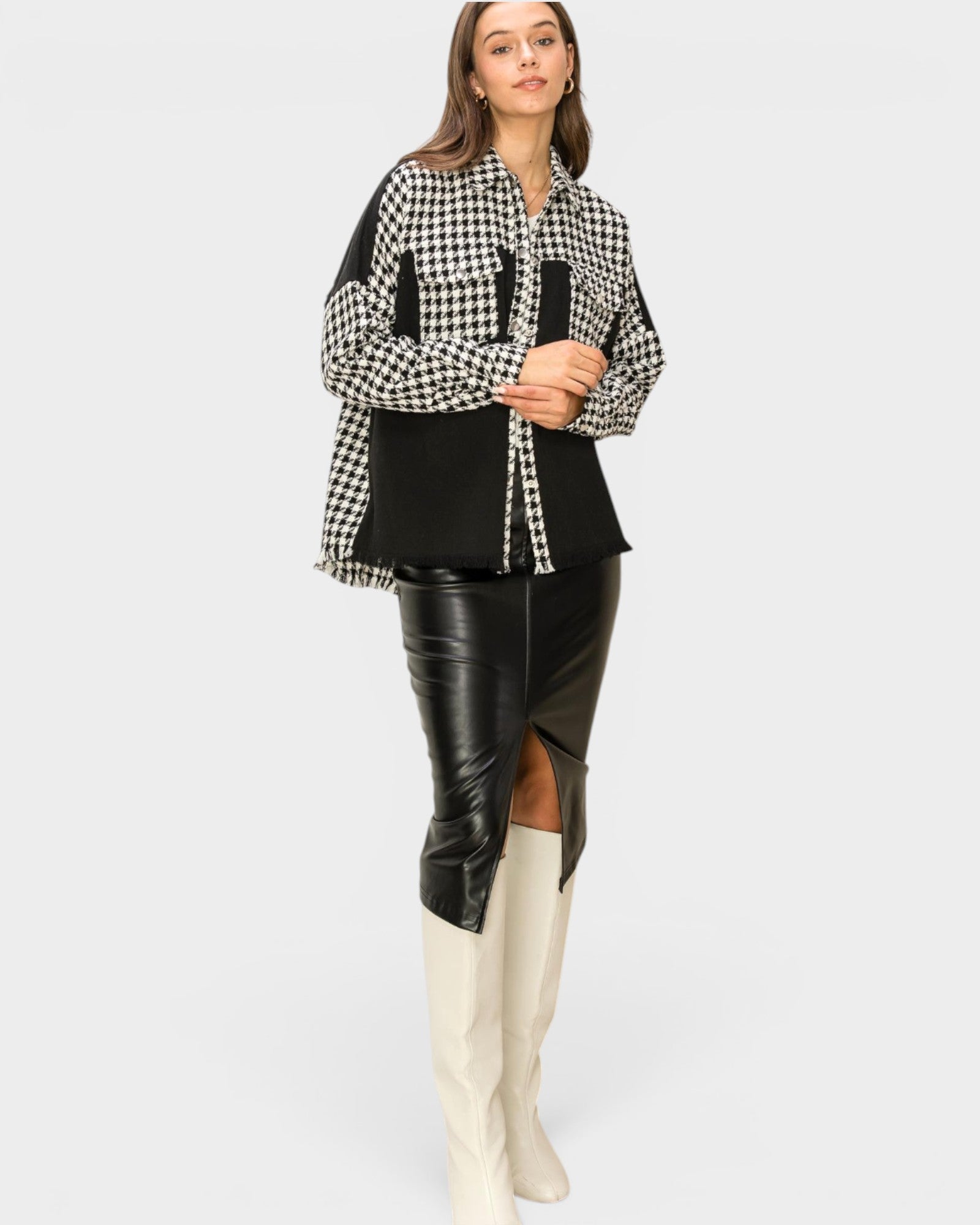 Woman wearing a checkered shirt, black leather skirt, and white knee-high boots on a white background