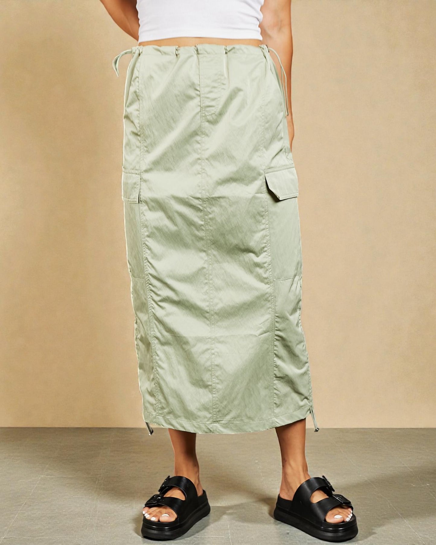 Person wearing a light green cargo skirt on a beige background