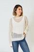 Woman wearing a cream-colored sweater with a textured pattern and blue jeans on a white background