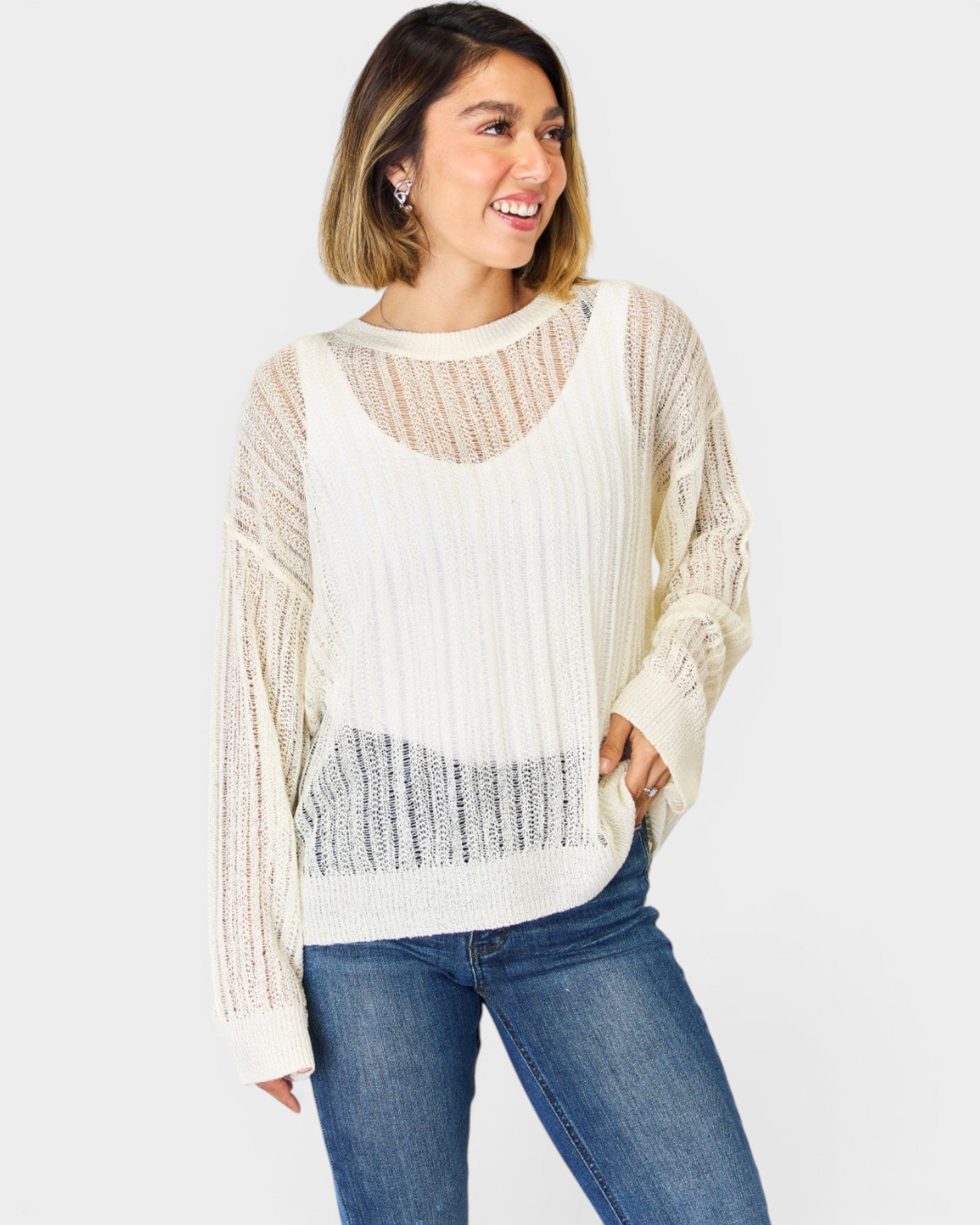 Woman wearing a white knit sweater and blue jeans on a white background