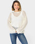 Woman wearing a cream sweater and blue jeans on a white background