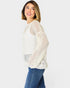 Woman wearing a white knit sweater and blue jeans on a white background