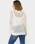 Woman wearing a white knit sweater with a patterned back on a white background