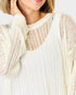 Close-up of a person wearing a textured white sweater on a light background