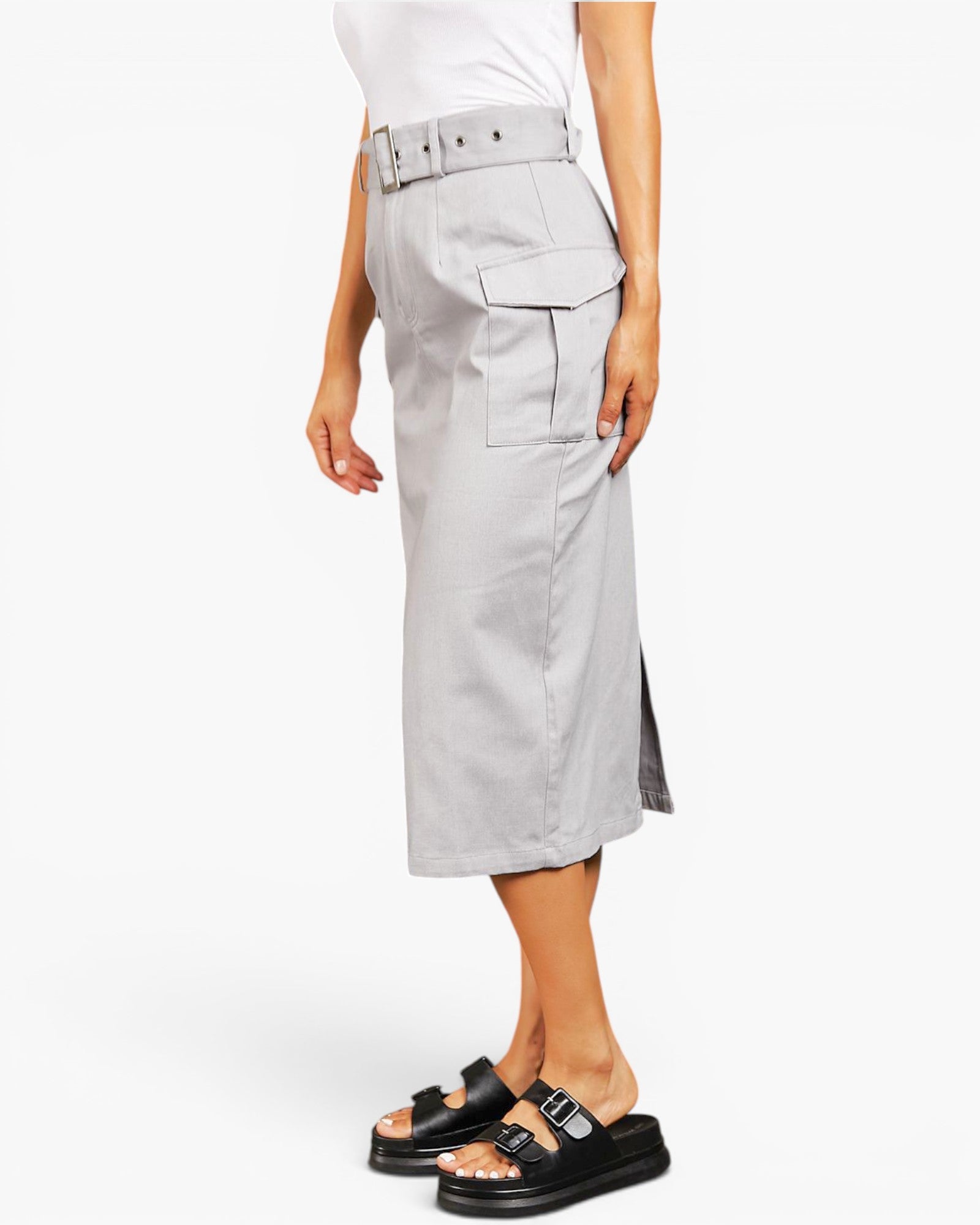 A model wearing a light gray cargo midi skirt with a matching belt, paired with a white top and black slide sandals, shown from the waist down on a white studio background.