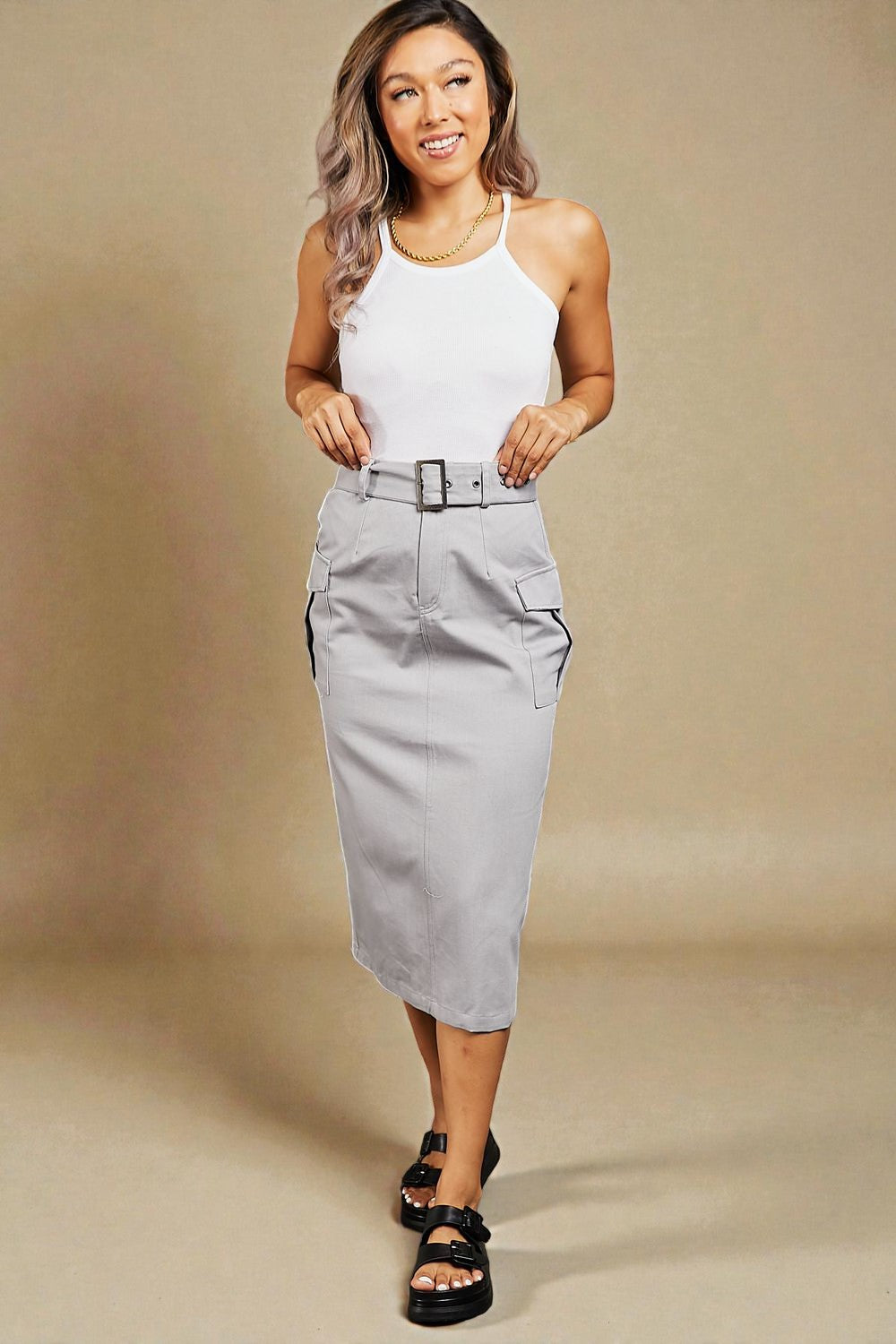 Woman wearing a white top and gray skirt against a beige background